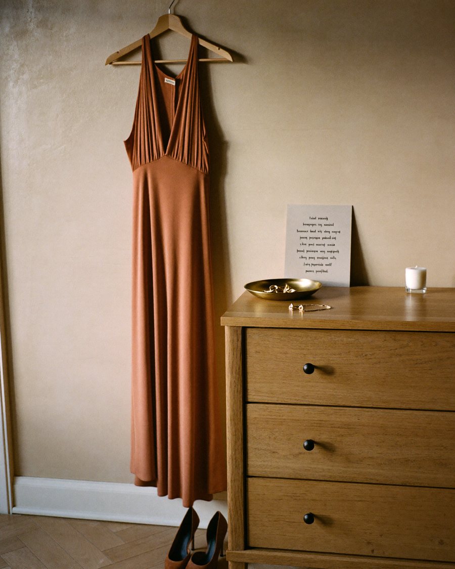 Rust-coloured evening dress on a hanger next to heels, ready for an occasion
